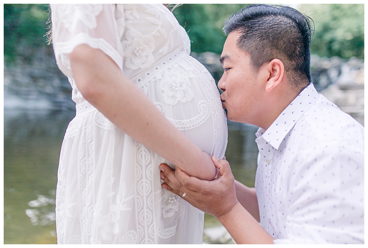 Husband kissing pregnant wife's belly at Prairie Creek Park for maternity session photographed by Dallas wedding and portrait photographer Jenny Bui of Picture Bouquet Studio. 
