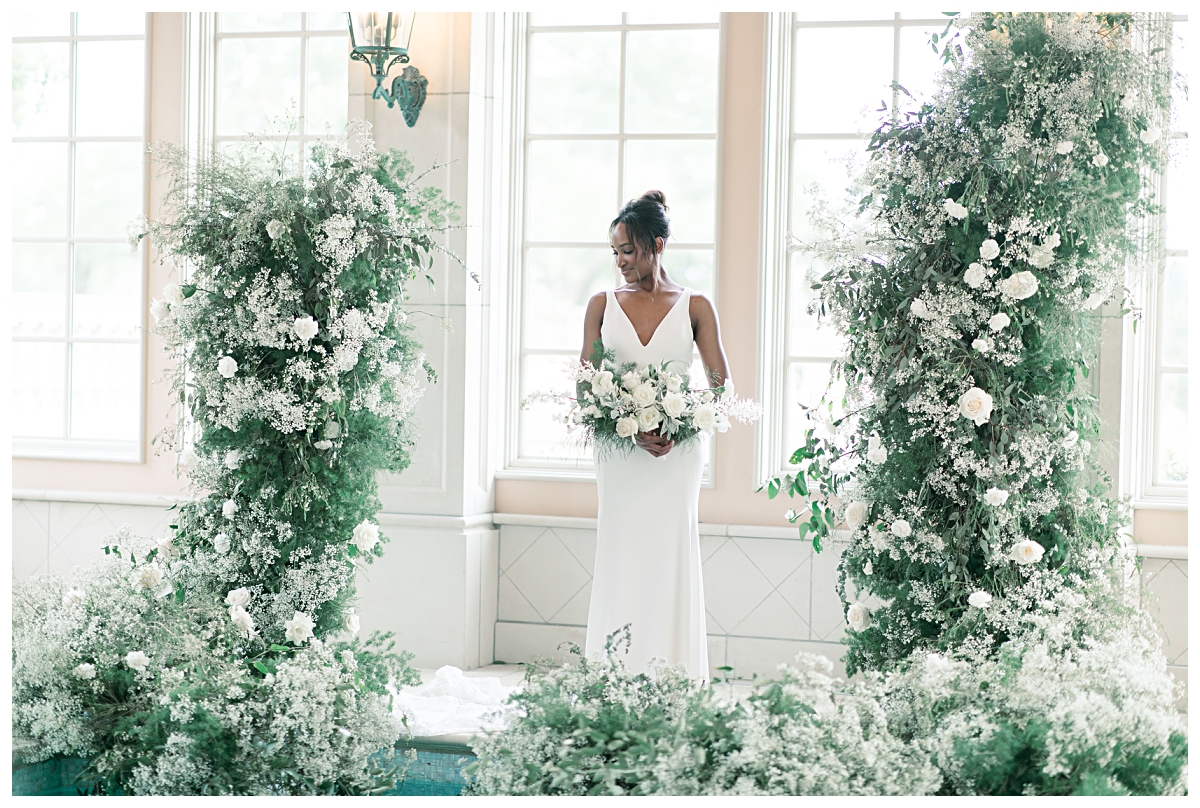 Bride in center of gorgeous floral arch at edge of pool for editorial bridal shoot at The Olana pool room photographed by Dallas wedding photographer Jenny Bui of Picture Bouquet Studio. 