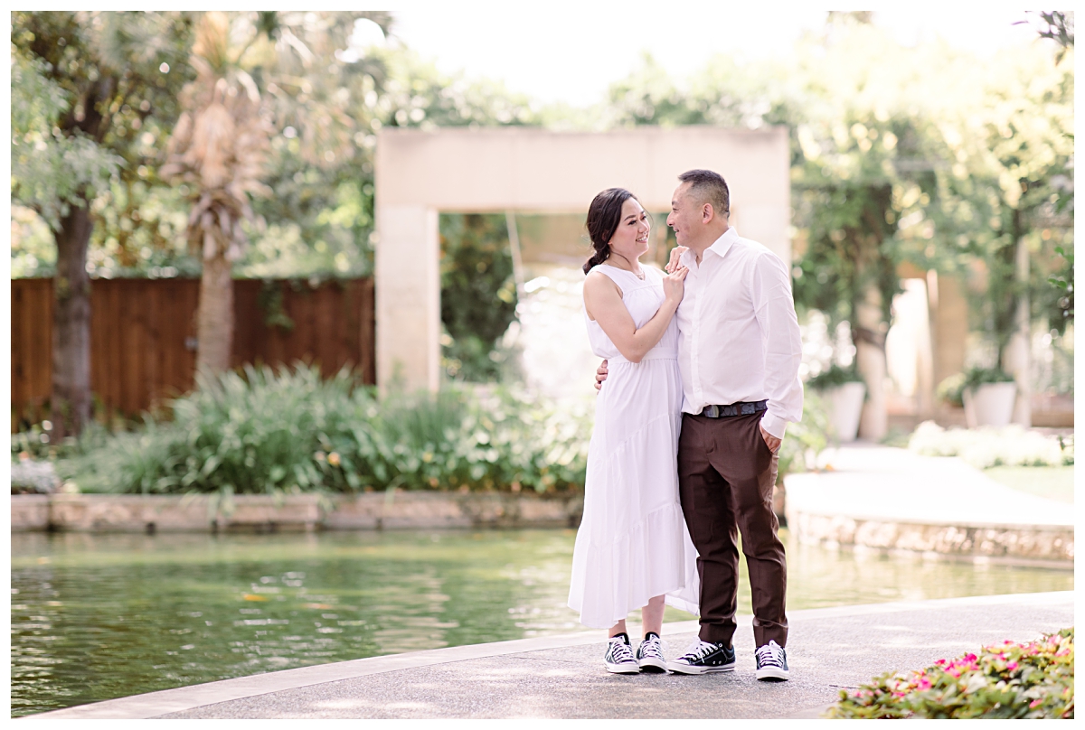 Engaged couple in white gazing at one another at Dallas Arboretum engagement session photographed by Picture Bouquet Studio.