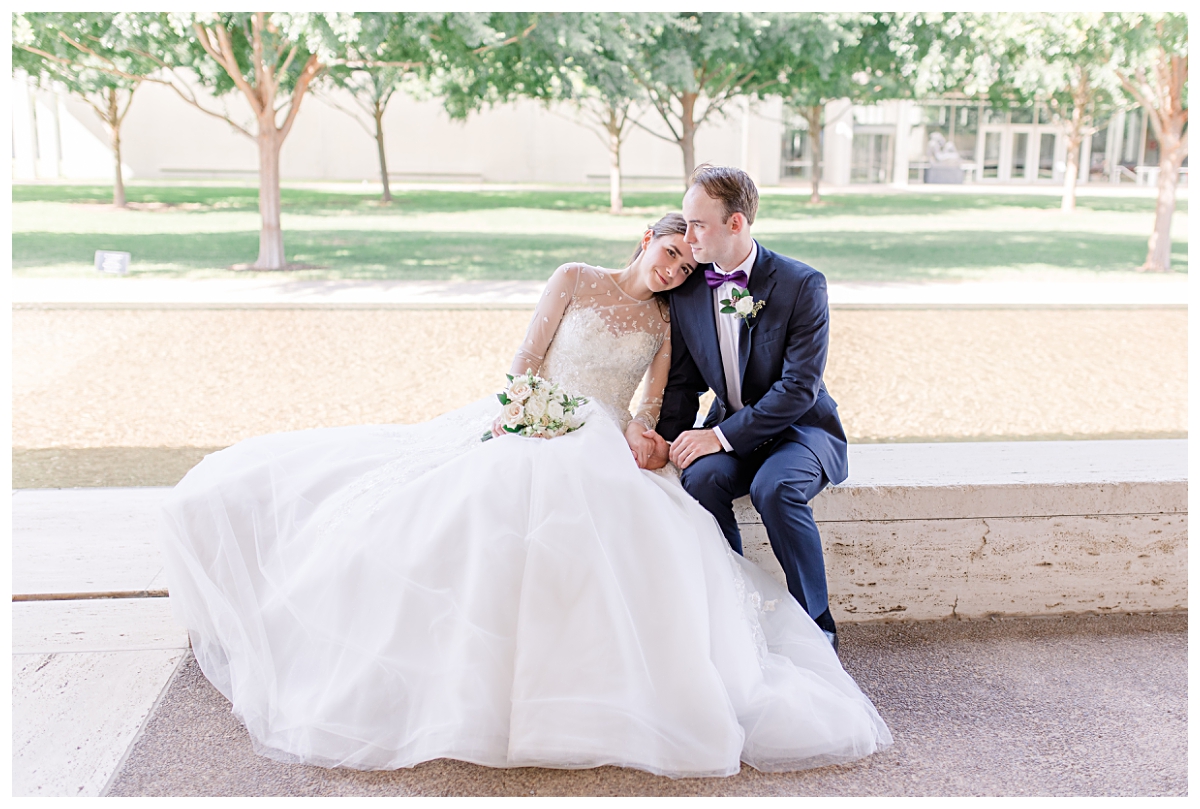 Bride in long sleeve white lace wedding gown leaning into groom in navy suit for Kimbell Art Museum wedding portraits photographed by Dallas wedding photographer Jenny Bui of Picture Bouquet Studio. 