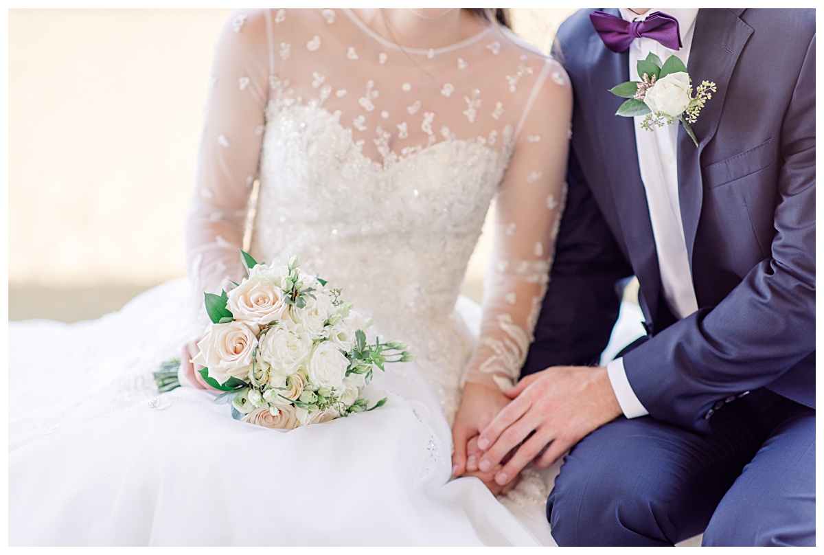 Close up of bride in long sleeve white lace wedding gown holding hands with groom in navy suit for Kimbell Art Museum wedding portraits photographed by Dallas wedding photographer Jenny Bui of Picture Bouquet Studio. 
