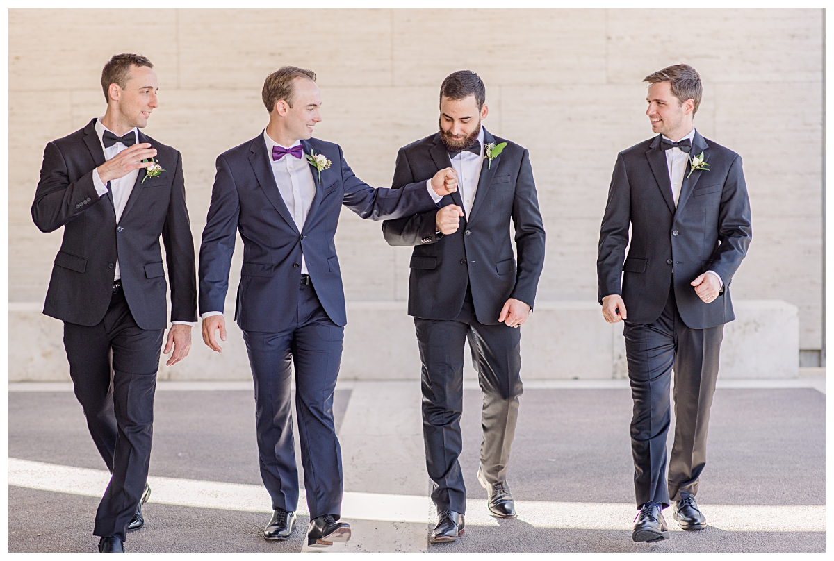 Groomsmen in black suit walking and congratulating groom in navy suit at Kimbell Art Museum for wedding day portraits photographed by Jenny Bui of Picture Bouquet Studio. 